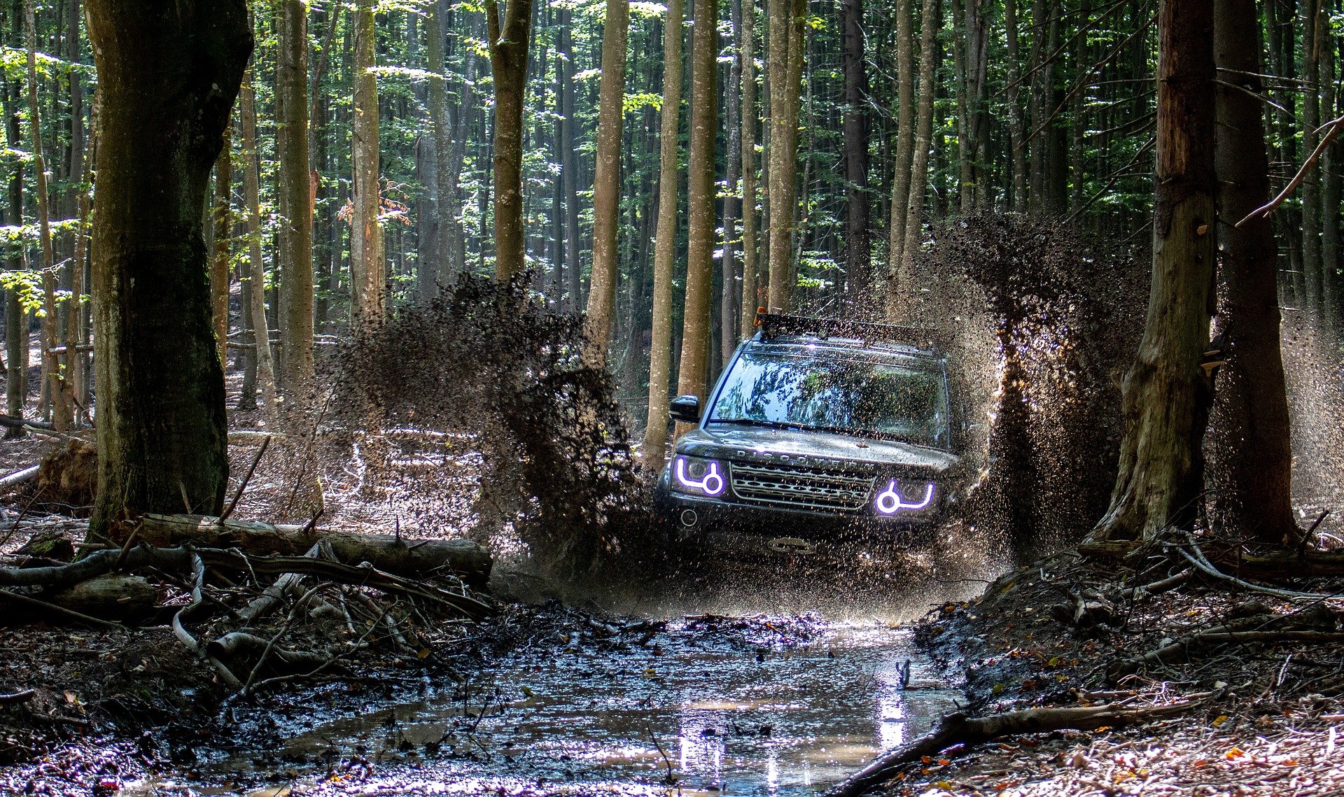 En Land Rover kjører i gjørme i skogen